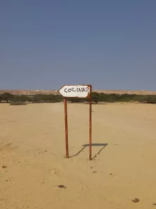 Ein Schild weist den Weg über die Sandpiste